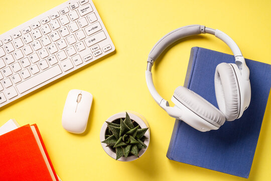 Office desk with headphones, notepad and pen at color background. Flat lay image with copy space. Office, studying, workspace.