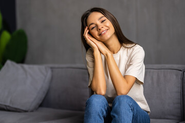 Happy young woman sitting on sofa at home and looking at camera.