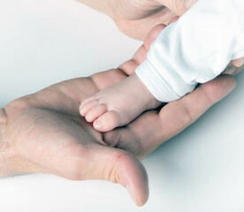 Father holding newborn baby in hands feet