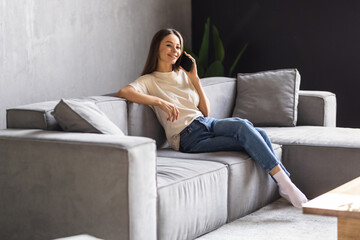 Obraz premium Happy young woman talking phone in loft apartment