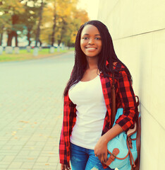 Fototapeta premium Portrait of young african woman with backpack on the city street