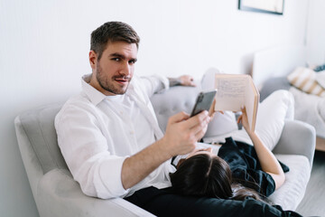 Serious man browsing smartphone on sofa