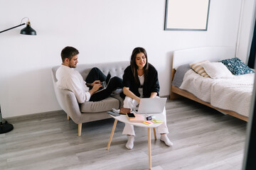 Cheerful couple working on laptop in modern living room