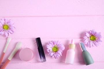 Cosmetic bottles with flowers on pink table, mockup