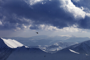 Fototapeta na wymiar Off-piste slope for heliskiing and helicopter in evening mountains