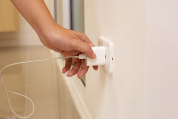 Hand insert a plug of the phone charger into socket. - obrazy, fototapety, plakaty