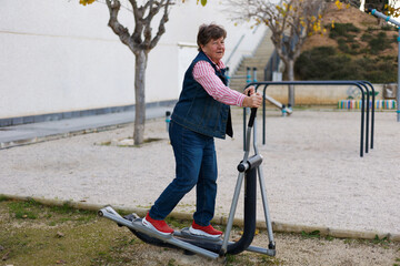 An elderly woman is engaged in sports on street simulators, Physical education in retirement