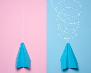 Two paper boats with different trajectories on a blue pink background, concept of goal achievement...