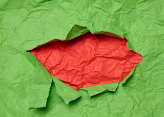 Texture of green paper with torn hole and red background, template for designer