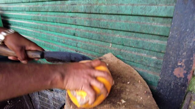 Man cuts the coconut with a knife to make a fresh coconut drinkon a market. Asia, Sri lanka, Kandy.