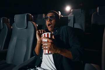 The man came to the meaning of the movie in the cinema with popcorn.