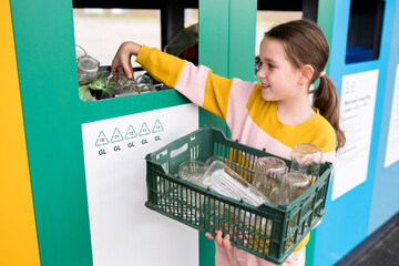 Recycling Week wiht kids. Girl dumping glass bottles in bank for reduce trash, reuse, recycle. Recyclability and sustainability concept.