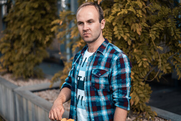 Happy man in the park on the background of plants. Casual clothes, urban style. People around us. Male portrait.