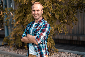 Happy man in the park on the background of plants. Casual clothes, urban style. People around us. Male portrait.