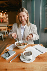 Cheerful businesswoman is having a business lunch during working day in cafe. Blurred background