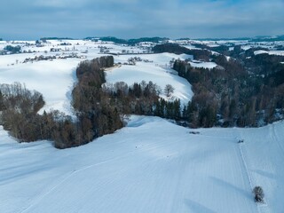 Fototapeta na wymiar Aerial view of snow covered rural area in Canton of Fribourg in Switzerland in winter.