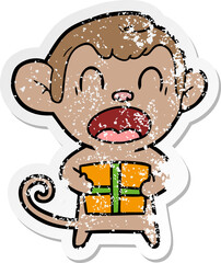 distressed sticker of a shouting cartoon monkey carrying christmas gift