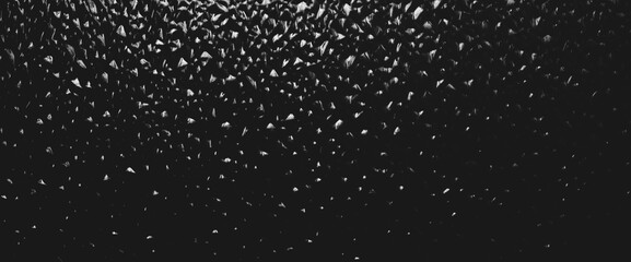 Corrugated window glass with light reflection in night. Atmospheric monochrome dark background. Shiny rippled glass glow in darkness close up. Detailed embossed texture in macro with copy space.