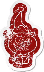 cheerful sitting pig cartoon distressed sticker of a wearing santa hat