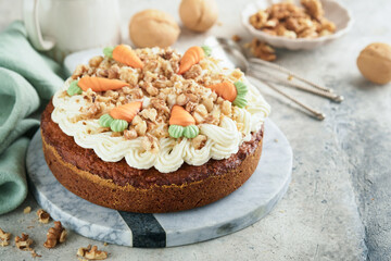 Fototapeta na wymiar Easter Carrot cake with cream cheese frosting. Delicious carrot cake with walnut and cream cheese frosting on gray concrete background table for festive dinner. Traditional carrot cake. Easter food.