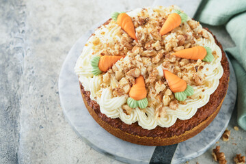 Easter Carrot cake with cream cheese frosting. Delicious carrot cake with walnut and cream cheese frosting on gray concrete background table for festive dinner. Traditional carrot cake. Easter food.