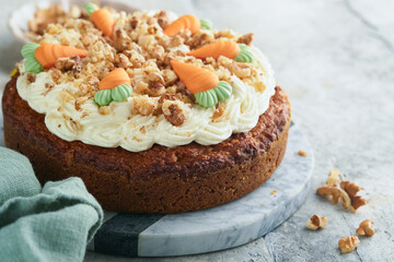 Easter Carrot cake with cream cheese frosting. Delicious carrot cake with walnut and cream cheese frosting on gray concrete background table for festive dinner. Traditional carrot cake. Easter food.