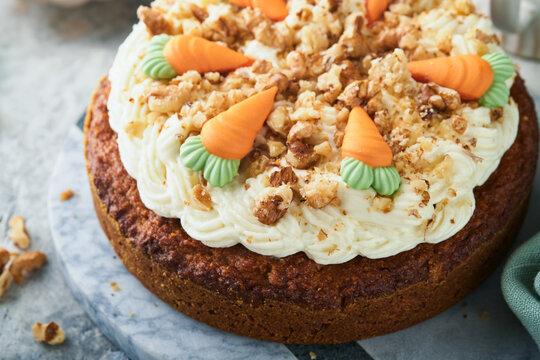 Easter Carrot cake with cream cheese frosting. Delicious carrot cake with walnut and cream cheese frosting on gray concrete background table for festive dinner. Traditional carrot cake. Easter food.