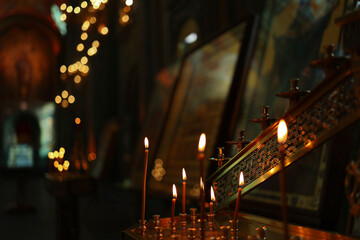 Burning candles on the background of Orthodox icons in a dark room of the church. Selective focus.