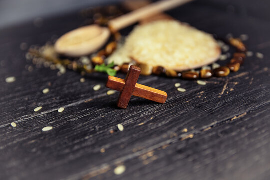 crucifix rosary and rice, Christian cross necklace on dark background - as a symbol of the beginning of Great Lent, Ash Wednesday	