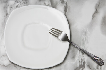 fork and plate on a light marble countertop