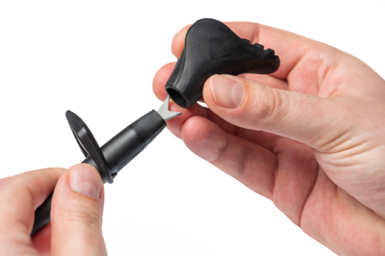 Hand with cane for Nordic walking isolated on white background. A man puts on a rubber tip or boot for use on asphalt or a hard surface close-up