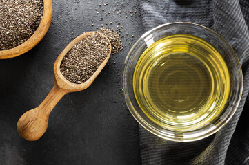 Glass bottle of Chia oil with Chia seeds ( Salvia Hispanica ) in wooden shovel on rustic background