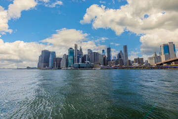Fototapeta premium Beautiful view at Manhattan from river side. Highscapers on blue sky with white clouds background. 