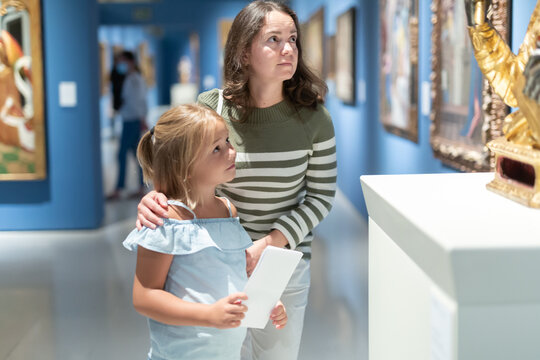 Glad mother and daughter exploring expositions in museum
