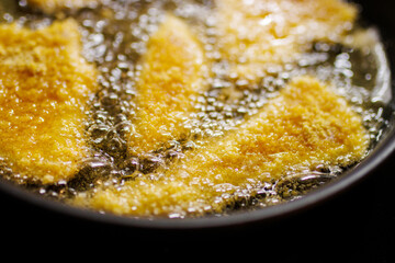 Deep frying chicken meat on a hot frying pan with a lot rapeseed oil. Very fat and unhealty christmas meal in czech republic.