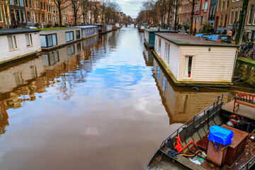 Fototapeta na wymiar Cityscape on a sunny winter day - view of the water canal with houseboats in the historic center of Amsterdam, the Netherlands