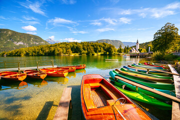 Fototapeta premium Moored colorful canoes and wooden boats on the Bohinj lake. Triglav national park, Slovenia, Europe.