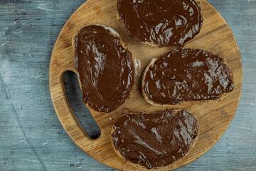 Flat lay above chocolate cream on the bread with dark moody blue background