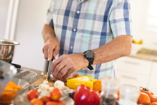 Midsection of senior caucasian man cooking dinner in kitchen