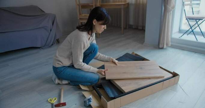 Woman assembles flat pack furniture in the living room