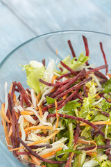 Fresh vegetables salad in the bowl above dark moody blue background