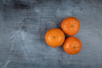 Three whole tangerines above dark blue food backgrounds