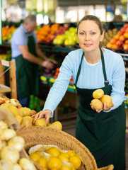 female seller selects quality medium-sized potato for buyer