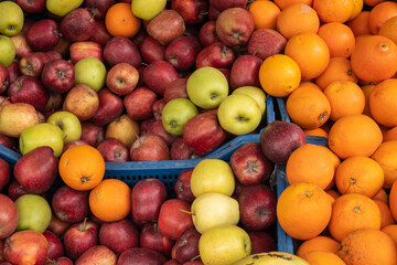 Heap of ripe apples and oranges in containers in market