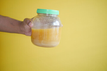 homemade ghee in container against yellow background 