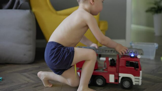 kid boy child playing toy fire truck car at home living room. little boy pretending being fireman play extinguish the fire imagine himself save life. children activity creative games indoors