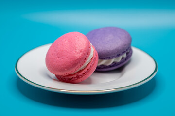 Close up plate of colorful French macaron confections with a cream filling, on a white background
