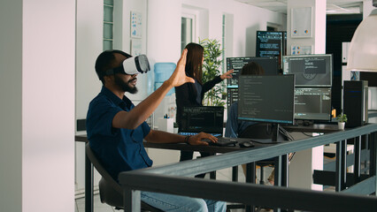 Male app developer using virtual reality glasses to code new server interface, analyzing cloud information on terminal window. Coder programming it database for internet software with vr headset.