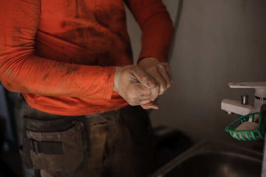 The mechanic washes his hands after car repair. Worker washes his hands