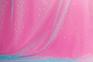 Abstract pink background with blue tulle and sequins.